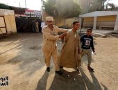 شرطى يساعد مواطنا من ذوى الهمم أثناء دخول لجنته الانتخابية فى العياط