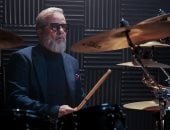 ببدلة أنيقة ولحية بيضاء.. شريف منير يلعب الدرامز فى أحدث جلسة تصوير