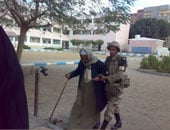 مجند يساعد "مسن" أثناء دخوله اللجنة للإدلاء بصوته فى المحلة