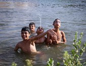 الأطفال يهربون من الحرارة المرتفعة بالاستحمام فى مياه النيل