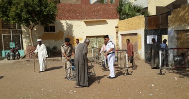 بالصور.. رجال تأمين لجنة انتخابية بأسوان يساعدون قعيدا للإدلاء بصوته