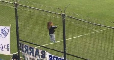 صورة اليوم.. طفلة تتسلق سياجا حديديا لمساندة فريقها بالأرجنتين