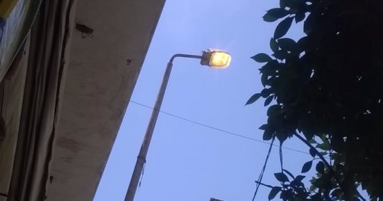 أعمدة الإنارة مضاءة نهاراً فى شارع السكة بالإسكندرية