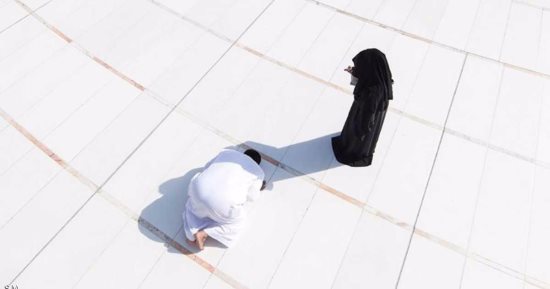 سعودى يصلى فى ظل زوجته بساحة الحرم المكى للوقاية من حرارة الشمس