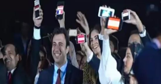 ضيوف منتدى شباب العالم يرفعون أعلام بلادهم على الهواتف المحمولة مع علم مصر