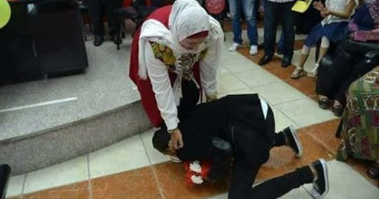 بالصور.. شاب يقبل قدم أمه بحفل تكريمها بعد بلوغها سن المعاش