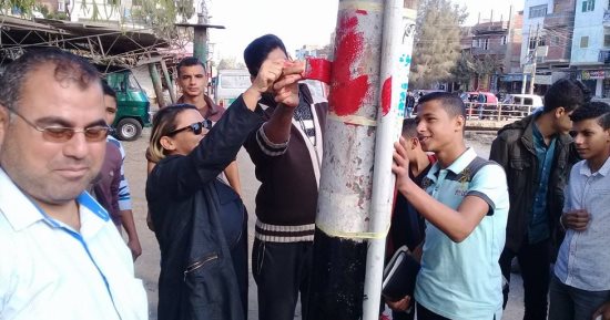 بالصور ...برازيلية تشارك شباب قرية أبو غنيمة دهان أعمدة الإنارة بكفر الشيخ