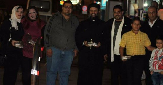 صور.. كاهن يشارك شباب "اسعد غيرك" توزيع حلوى المولد النبوى ببورسعيد