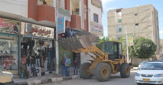 صور .. إزالة منشآت غير آمنة وإعلانات مخالفة بمدينة الخارجة بالوادى الجديد