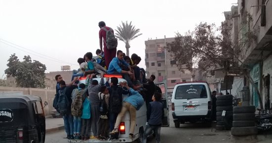 طلاب البراجيل بالجيزة يتعلقون بسيارة ميكروباص للذهاب لمدارسهم