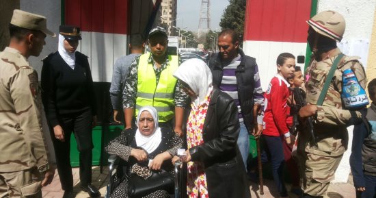 صور.. الشرطة توفر كرسى متحرك لنقل مسنة إلى لجنتها فى الساحل