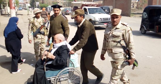 صور .. رجال الجيش يساعدون مُسن للإدلاء بصوته داخل لجنة بمنيا القمح
