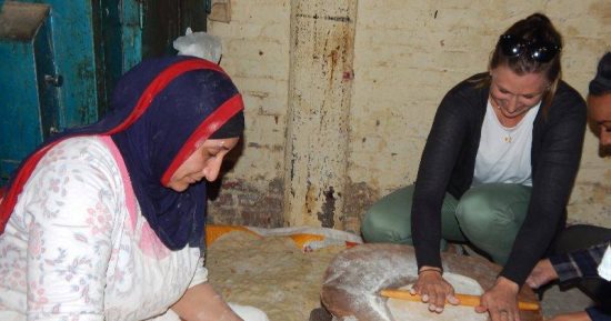 شاهد.. سياح أمريكان يتجولون بشوارع فوة ويشاركون فى صناعة المخبوزات والسجاد