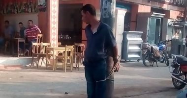 صور.. أهالى الحورانى بدمياط يقيدون لص بطاريات على عمود إنارة 