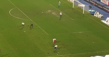 فيديو وصور .. عمال برج العرب يصلحون الأرضية بين شوطي مواجهة الأهلي والزمالك