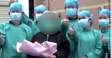 مرضى تعافوا من كورونا يلتقطون صورا مع الأطقم الطبية بمستشفى صيني.. فيديو