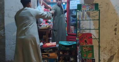 لحمايتك وحمايتى من كورونا.."بقال" بالأقصر يصنع حاجز بالكراتين بينه وبين زبائنه