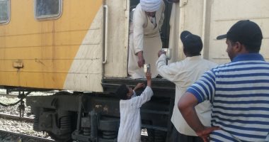أهالى نجع أبو ريش يقدمون الماء البارد لركاب قطار في أسوان.. صور