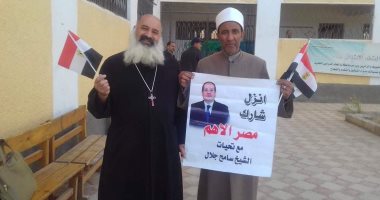 شيخ وقس يرفعان لافتة تدعو الناخبين للمشاركة فى الانتخابات البرلمانية بالمنيا