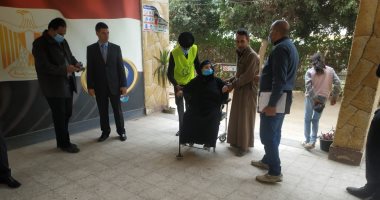 قوات التأمين تساعد مسنة على الإدلاء بصوتها بجولة الإعادة فى القليوبية