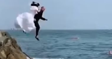 عروسان أيرلنديان يحتفلان بزواجهما بالقفز فى البحر بملابس الزفاف..فيديو وصور