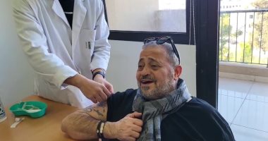 خدها بضحكة.. جورج وسوف يسلطن الفريق الطبى بأغنية "لقحونى" خلال تطعيمه.. فيديو