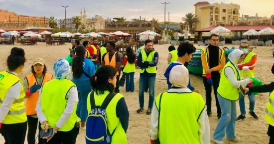 طاقم أكبر مكتبة عائمة في العالم ينظفون شاطئ بورسعيد.. صور