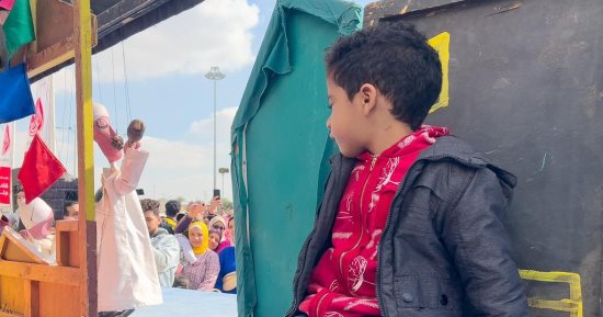 العرض شد انتباهه.. طفل يتابع "الليلة الكبيرة" من الكواليس فى معرض الكتاب