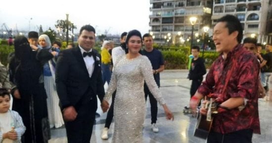سائح ياباني يعزف مقطوعة موسيقية لعروسين بساحة مصر في بورسعيد.. صور