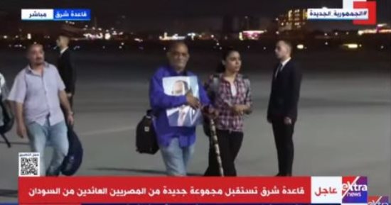 مواطن عائد من السودان يحمل صورة الرئيس السيسي لدى وصوله مطار قاعدة شرق