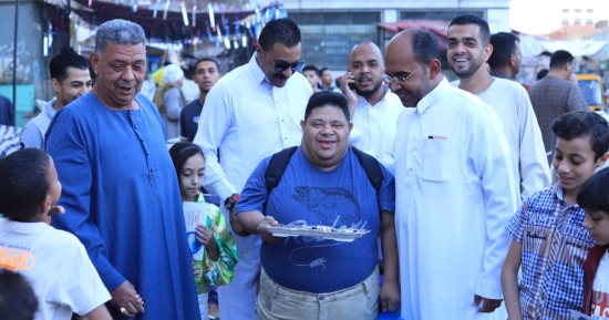 شاب قبطى من ذوى الهمم يوزع الحلوى للأهالى احتفالا بعيد الفطر فى الأقصر.. صور