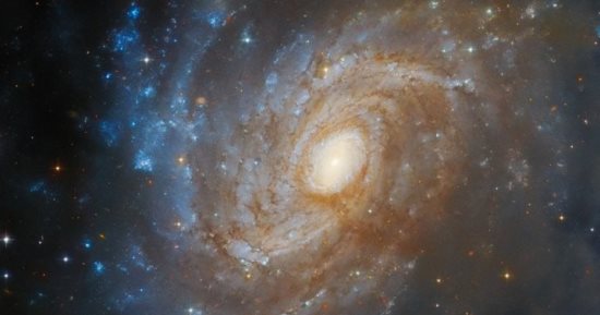 تلسكوب هابل يرصد مجرة ​​لامعة تنبثق من خلف سديم مظلم