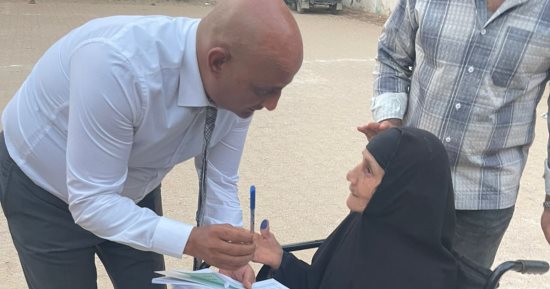 رئيس لجنة بالفيوم يتوجه إلى مسنة خارج اللجنة لمساعدتها على الإدلاء بصوتها