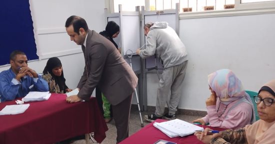 رئيس لجنة فرعية يساعد الناخبين على معرفة رقمهم الانتخابى فى المطرية
