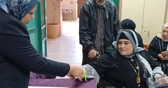 رئيسة لجنة بأسوان تساعد سيدة من ذوى الاحتياجات على الإدلاء بصوتها.. صور