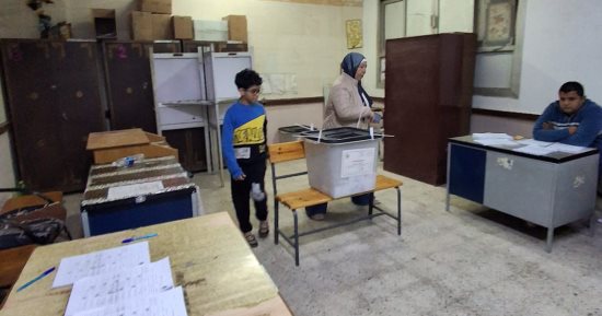 سيدة تصطحب نجلها في الساعات الأخيرة قبل غلق التصويت بحدائق القبة
