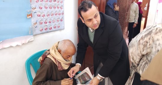 رئيس لجنة فرعية بالمطرية يساعد ناخب مسن على الإدلاء بصوته ويحضر كرسى له