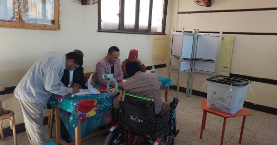 رئيس لجنة بجولة إعادة انتخابات النواب بمركز بلاط يساعد ناخب على كرسى متحرك للإدلاء بصوته
