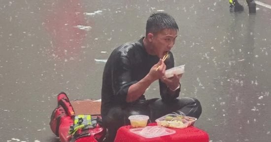 رجل إطفاء يتناول طعامه تحت المطر خلال إنقاذ ضحايا الفيضانات فى الصين