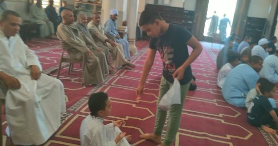 طفل يوزع الحلوى احتفالا بقدوم المولد النبوى فى مسجد العتيق جنوب الأقصر.. صور
