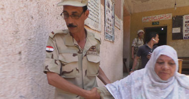 أحد رجال الجيش يساعد سيدة مسنة داخل لجنة بشبرا